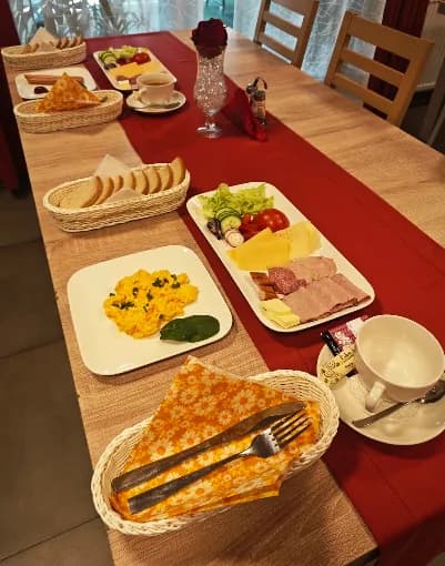 Śniadanie w formie bufetu — jajecznica, wędliny, sery i pieczywo na stole